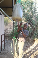 Here our tent attendant has filled the bucket shower with hot water and is hoisting it up above the tent so it will gravity feed the shower